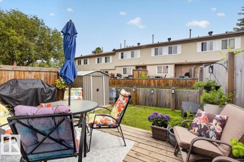 Outdoor patio featuring wood decking, a privacy fence, and an adjacent green space - 27 Walden Park, St. Albert, AB 