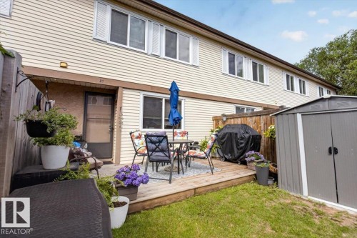 Private backyard featuring a wooden deck with a sliding glass door entry, a manicured lawn, and a metal storage shed - 27 Walden Park, St. Albert, AB 