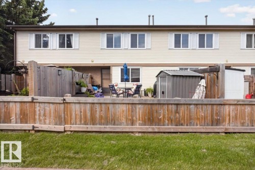 Private fenced yard space featuring a patio area, mature perimeter trees, and a wooden privacy fence - 27 Walden Park, St. Albert, AB 