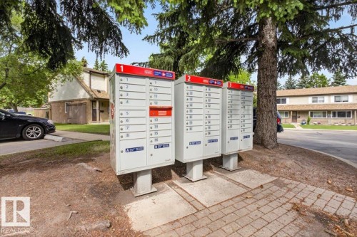 Community mailbox units on a paved brick surface with established trees and surrounding residential structures - 27 Walden Park, St. Albert, AB 