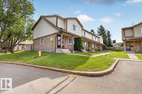 Townhome exterior featuring a two-story design with a pitched roofline, stucco and siding finishes, and mature landscaping - 27 Walden Park, St. Albert, AB 