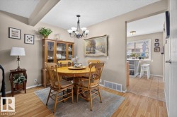 Dining area featuring wood-finish flooring, a contemporary chandelier, and a built-in display cabinet - 