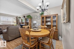 Open-concept living and dining area featuring wood-finish flooring, a decorative chandelier, and a large window with horizontal blinds - 