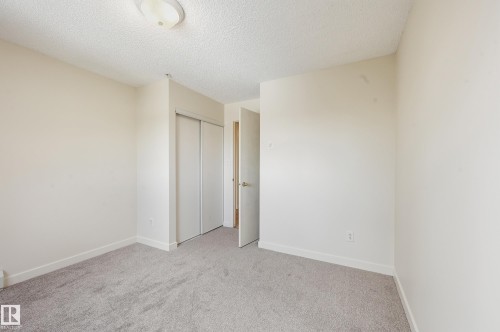 Carpeted room with sliding closet doors, white trim, and a flush-mount ceiling light - 314 2430 Guardian Road, Edmonton, AB 
