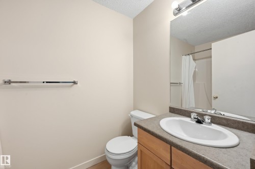 Bathroom with a light wood-finish vanity, integrated white oval sink, and a speckled gray countertop - 314 2430 Guardian Road, Edmonton, AB 