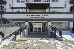 Building entrance featuring double glass doors, a concrete ramp with black metal railings, and cream-colored siding - 