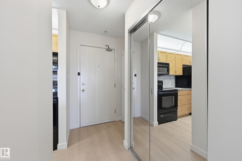 Entryway featuring wood-finish flooring, a white entry door, and a mirrored closet - 314 2430 Guardian Road, Edmonton, AB 