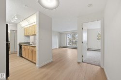 Open-concept living area featuring light wood-finish flooring, white walls, and a private balcony - 