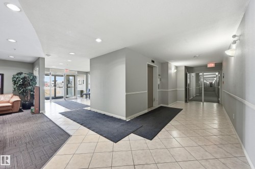 Building entryway featuring glass double doors, light-toned tile flooring, and recessed lighting - 314 2430 Guardian Road, Edmonton, AB 