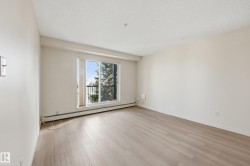 Bright room featuring light wood-finish flooring and a sliding glass door opening to a balcony with black railings - 