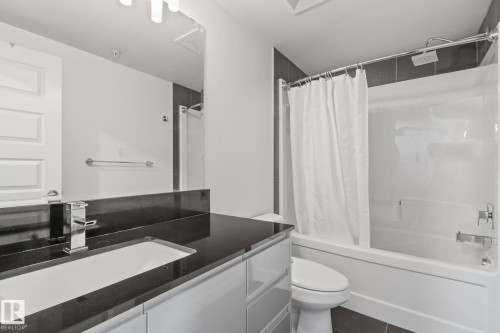 Bathroom featuring a vanity with dark countertop, undermount sink, and chrome faucet - 201 10388 105 Street, Edmonton, AB 