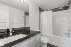 Bathroom featuring a vanity with dark countertop, undermount sink, and chrome faucet - 
