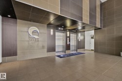 Lobby area featuring large format floor tiles, paneling with a wood-finish, stone-look wall panels, and two stainless steel elevators - 