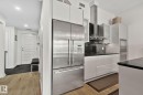 Modern kitchen featuring stainless steel appliances, white cabinetry, black countertops, and a built-in oven and microwave - 201 10388 105 Street, Edmonton, AB 