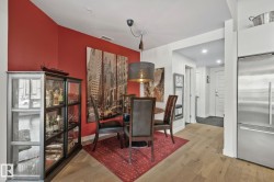 Dining area featuring an accent wall, wood-finish flooring, a built-in display cabinet with glass doors, and a decorative pendant light fixture - 