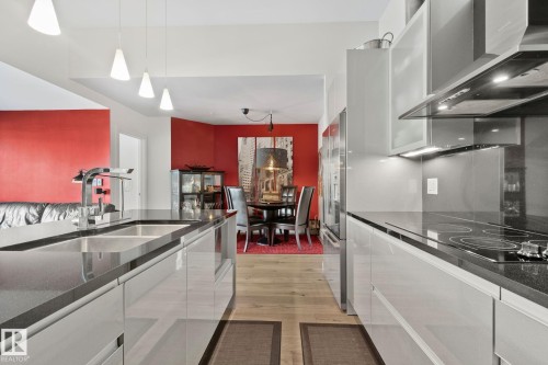 Modern kitchen featuring light wood-finish flooring, sleek cabinetry, dark countertops, and stainless steel appliances - 201 10388 105 Street, Edmonton, AB 
