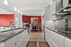 Modern kitchen featuring light wood-finish flooring, sleek cabinetry, dark countertops, and stainless steel appliances - 