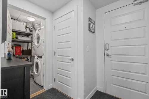 In-unit laundry closet featuring stacked appliances and built-in shelving - 201 10388 105 Street, Edmonton, AB 
