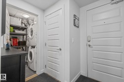In-unit laundry closet featuring stacked appliances and built-in shelving - 
