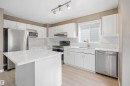 Kitchen featuring a central island with a white countertop, white cabinetry, stainless steel appliances, a subway tile backsplash, and light wood-finish flooring - 2610 33A Street, Edmonton, AB  - Indoor Photo Showing Kitchen With Upgraded Kitchen 