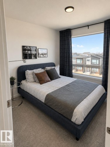Bedroom featuring expansive window with dark drapery, neutral carpet flooring, and a flush-mount ceiling light - 311 32 Street, Edmonton, AB 