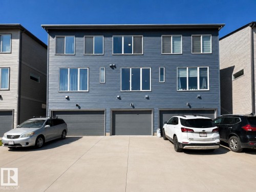 Contemporary three-story building featuring blue horizontal siding and multiple white-framed windows - 311 32 Street, Edmonton, AB 