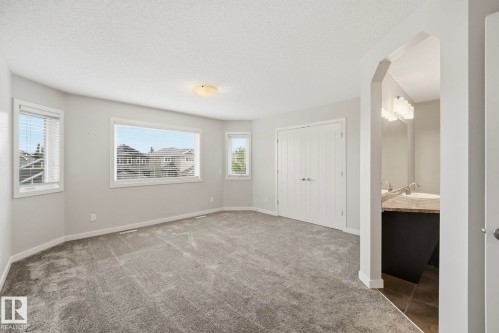 Spacious room featuring multiple windows with blinds, light gray wall paint, and a textured gray carpet - 33 Riviere Terrace, St. Albert, AB 