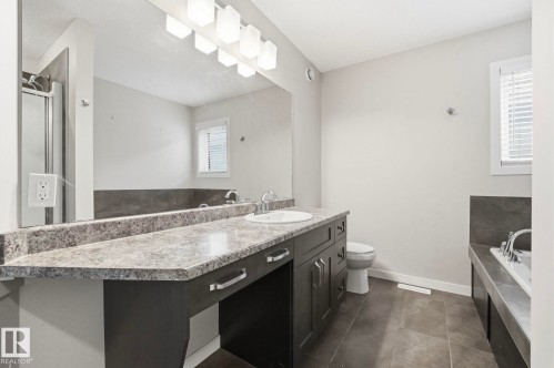 Bathroom featuring a double vanity with a speckled countertop, integrated sink, and modern cabinetry - 33 Riviere Terrace, St. Albert, AB 