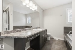 Bathroom featuring a double vanity with a speckled countertop, integrated sink, and modern cabinetry - 