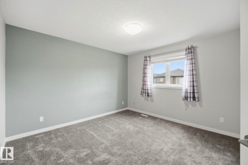 Carpeted room featuring a single window, a textured ceiling, and a flush mount ceiling light - 33 Riviere Terrace, St. Albert, AB 