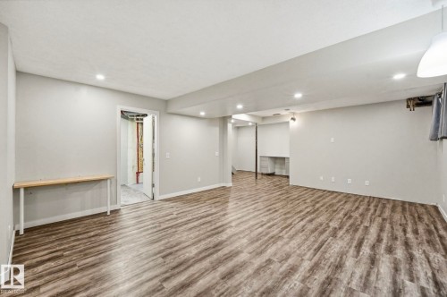 Expansive room featuring wood-finish flooring, recessed lighting, neutral wall tones, and a built-in desk area - 33 Riviere Terrace, St. Albert, AB 