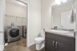 Bathroom featuring a dark wood-finish vanity with a speckled countertop and an undermount sink - 