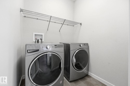 Dedicated laundry space featuring a wire shelving unit, durable tile flooring, and clean white walls - 33 Riviere Terrace, St. Albert, AB 