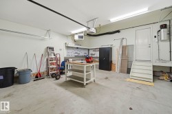 Concrete floor garage with ample wall space, overhead lighting, and an overhead garage door track system - 