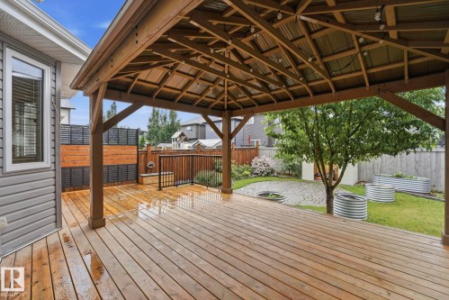 Expansive wood-finish deck featuring a built-in gazebo with a corrugated metal roof and string lighting - 33 Riviere Terrace, St. Albert, AB 
