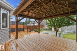 Expansive wood-finish deck featuring a built-in gazebo with a corrugated metal roof and string lighting - 