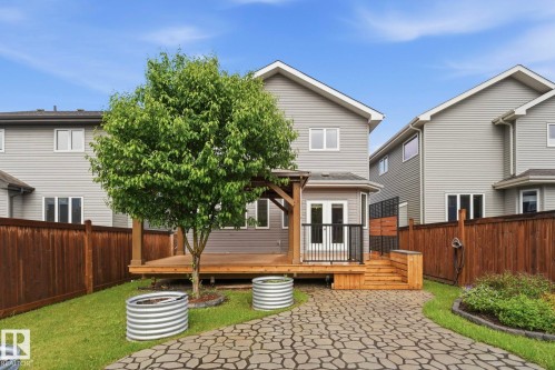 Backyard featuring a wooden deck with black metal railings, a stone-paved patio, and a mature deciduous tree - 33 Riviere Terrace, St. Albert, AB 