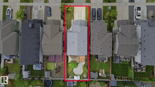 Property with a gray shingle roof, featuring a concrete driveway, a wood deck, a patio area with pavers, a lush green lawn, and mature landscaping - 33 Riviere Terrace, St. Albert, AB 