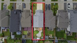 Property with a gray shingle roof, featuring a concrete driveway, a wood deck, a patio area with pavers, a lush green lawn, and mature landscaping - 