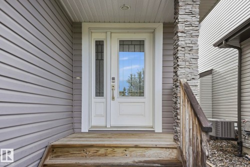 Entryway featuring a white door with decorative glass, a side light with patterned glass, and a stone-clad pillar - 33 Riviere Terrace, St. Albert, AB 