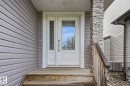 Entryway featuring a white door with decorative glass, a side light with patterned glass, and a stone-clad pillar - 33 Riviere Terrace, St. Albert, AB 