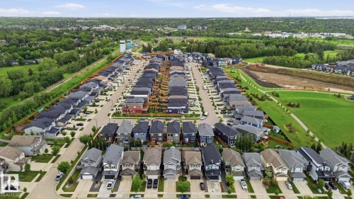 Aerial perspective of a modern residential development featuring numerous single-family homes with varied architectural styles and dark-toned roofs - 33 Riviere Terrace, St. Albert, AB 