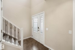 Entryway featuring a double door with decorative glass inserts, ceramic tile flooring, and a staircase with a white wood railing and metal balusters - 