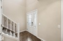Entryway featuring a double door with decorative glass inserts, ceramic tile flooring, and a staircase with a white wood railing and metal balusters - 33 Riviere Terrace, St. Albert, AB 