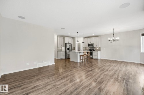 Open-concept living area featuring wood-finish flooring, recessed ceiling speakers, and a modern kitchen - 33 Riviere Terrace, St. Albert, AB 