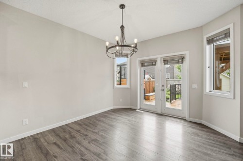 Spacious room featuring wood-finish flooring, a contemporary chandelier, neutral wall tones, and white trim - 33 Riviere Terrace, St. Albert, AB 