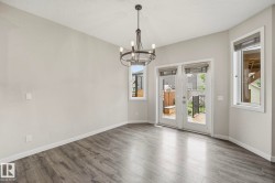 Spacious room featuring wood-finish flooring, a contemporary chandelier, neutral wall tones, and white trim - 