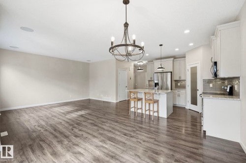Spacious open-concept area featuring wood-finish flooring, a contemporary chandelier, and recessed lighting - 33 Riviere Terrace, St. Albert, AB 