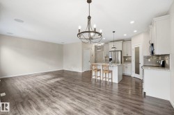 Spacious open-concept area featuring wood-finish flooring, a contemporary chandelier, and recessed lighting - 
