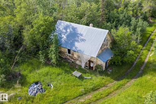 Rural residence featuring a metal roof and wood siding, surrounded by mature trees and natural vegetation - 23327 Twp Rd 510, Rural Leduc County, AB 